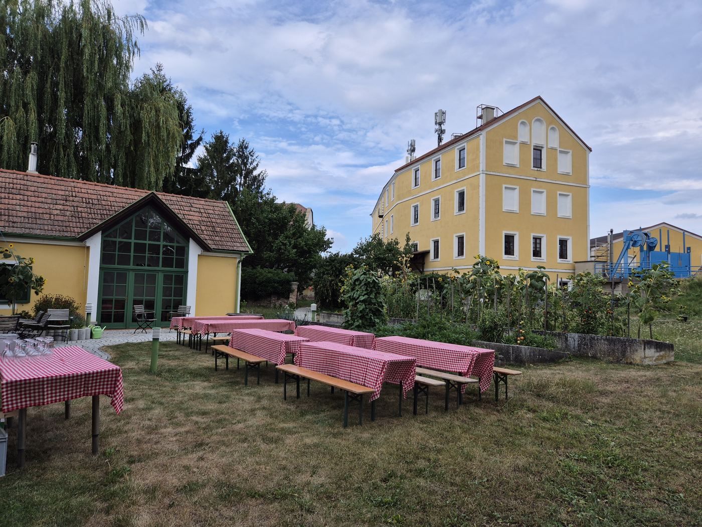 Gedeckte Tische im Garten vor dem historischen Mühlengebäude des Wasserkraftwerks Breitenau